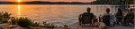 Friends and a Labrador relaxing on a backyard dock at sunset