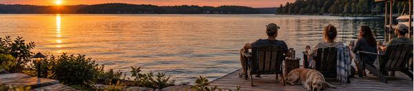 Friends and a Labrador relaxing on a backyard dock at sunset