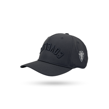 A dark charcoal gray baseball cap with 'COVERT' embroidered in tonal black on the front and a small silver shield logo on the side, shown on a white background with a soft shadow.