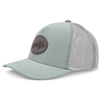 A sage green CLASSIC MESH  hat with a curved brim, featuring a light green front panel, a darker green mesh back, and a brown oval patch on the front with the brand name 'covelife' in script.