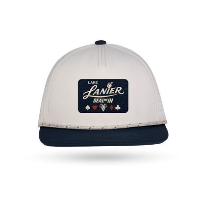 A two-tone snapback cap with an off-white crown and a navy blue flat brim. The front features a dark navy rectangular patch with the text LAKE LANIER "DEAL ME IN" and playing card symbols.