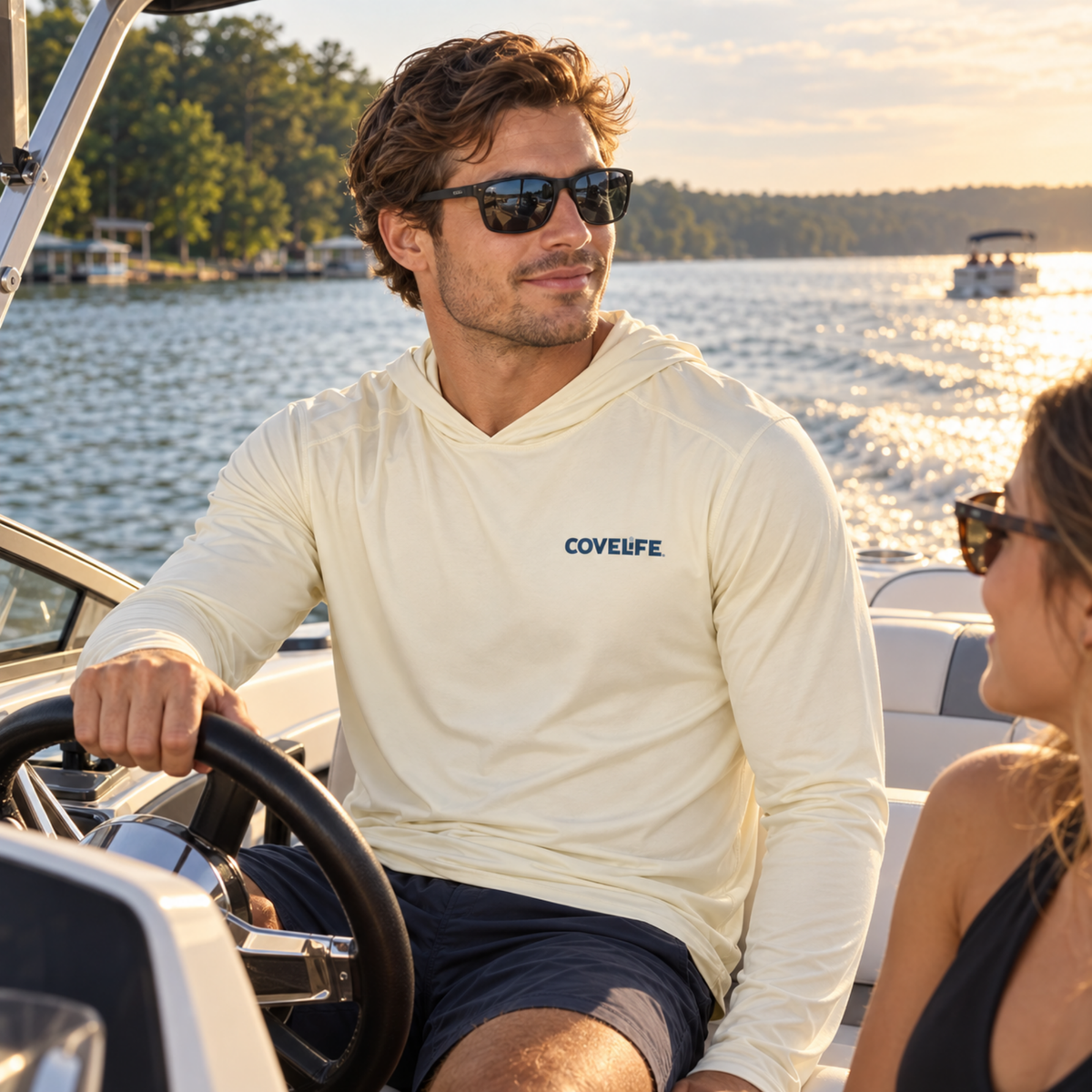 Man wearing the Sandbar COVELiFE SolarTech UPF 50+ Sun Hoodie while driving a boat at sunset.