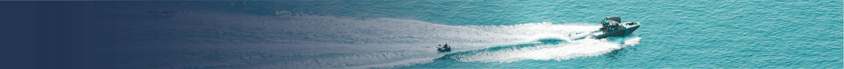Aerial view of two small boats moving across turquoise blue water, leaving white wakes behind them.