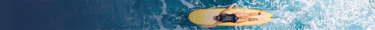 A person in a black swimsuit stands on a yellow surfboard in blue ocean water with white waves.